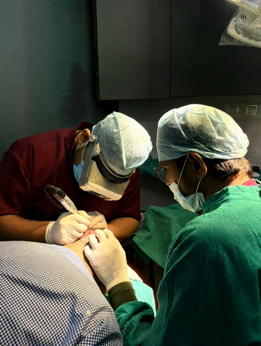 Dr. Atul taking grafts under magnification with an assistant
