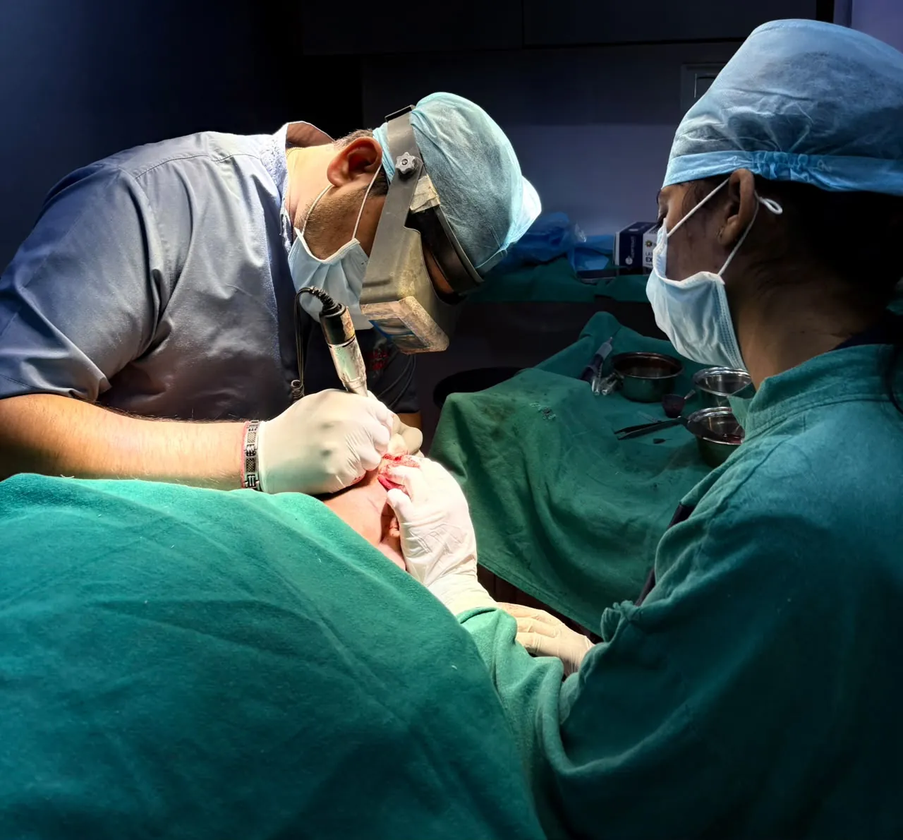 Dr. Atul Bhanu Singla working under magnification, with an assistant beside him